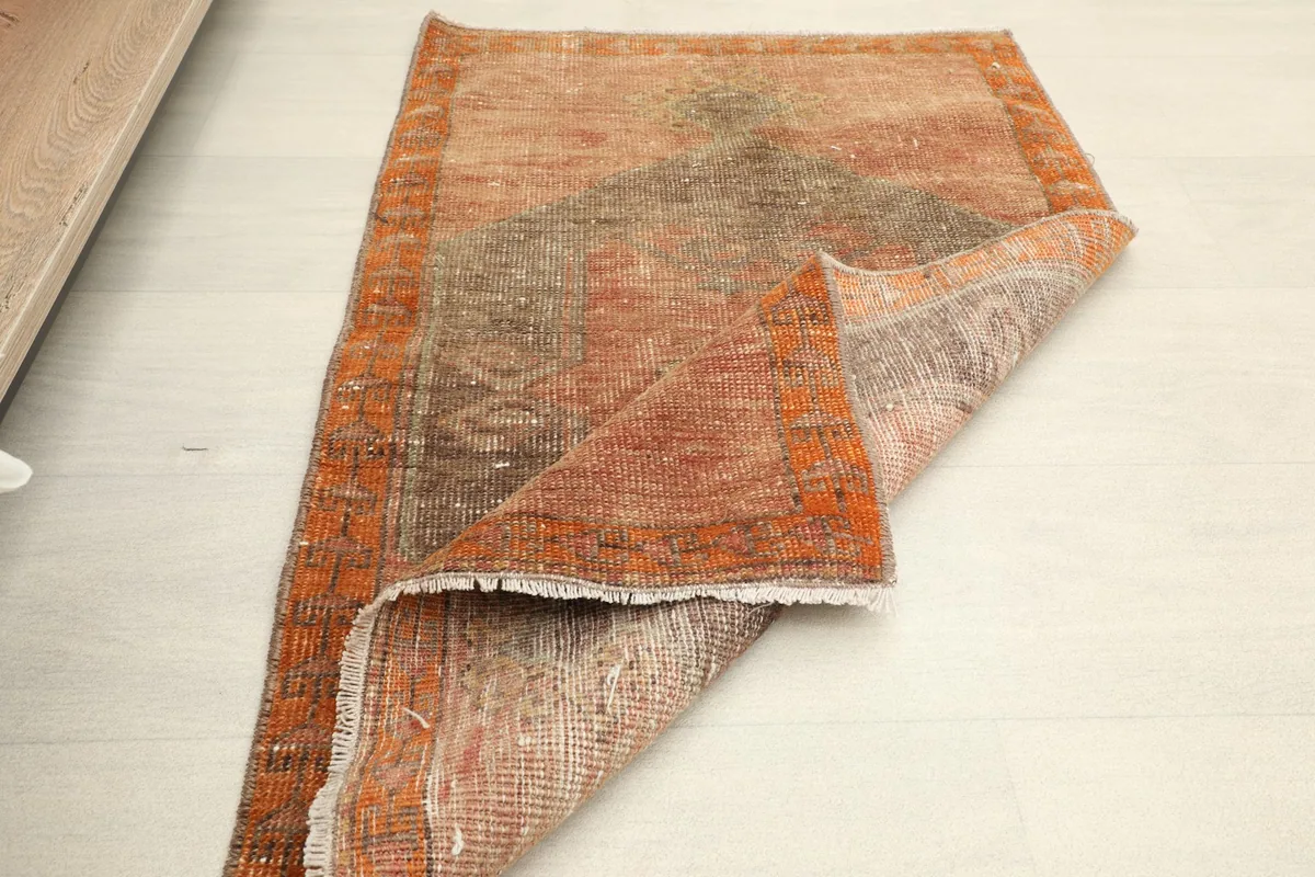 The small area rug partially folded, demonstrating its size and flexibility in a room setting.