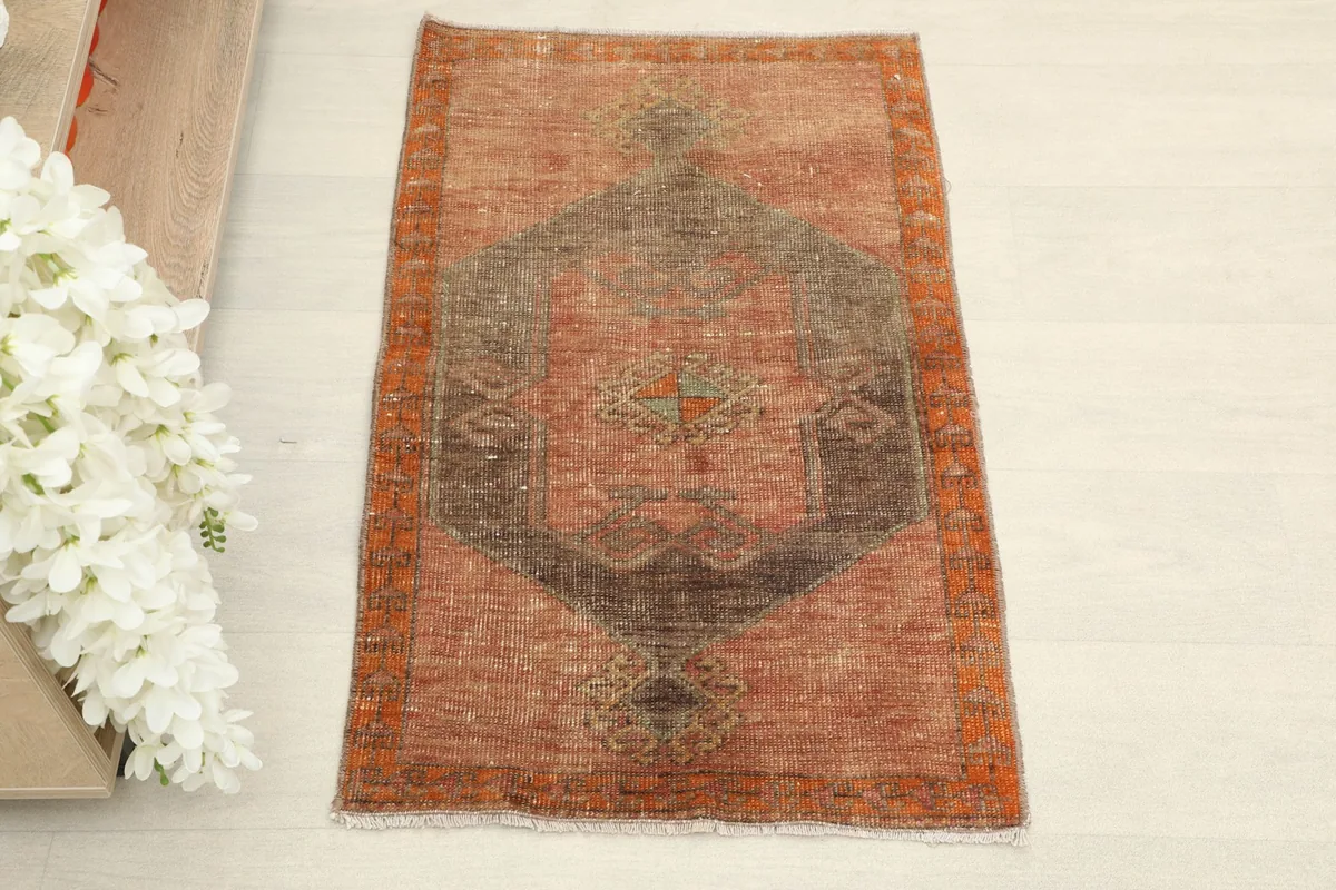 Overhead view of the small Anatolian rug, showing its rust and brown geometric pattern.