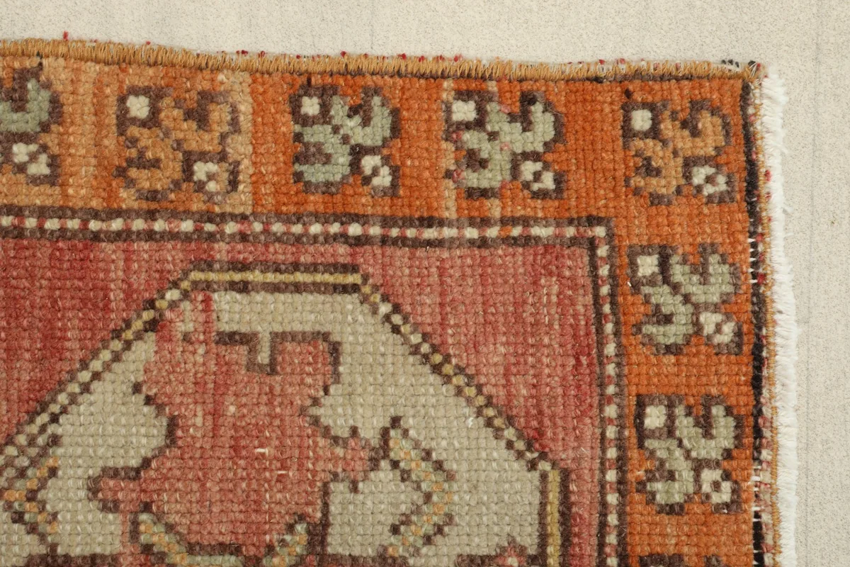 Close view of the orange border and a section of the main field, revealing the rug's texture and colors.