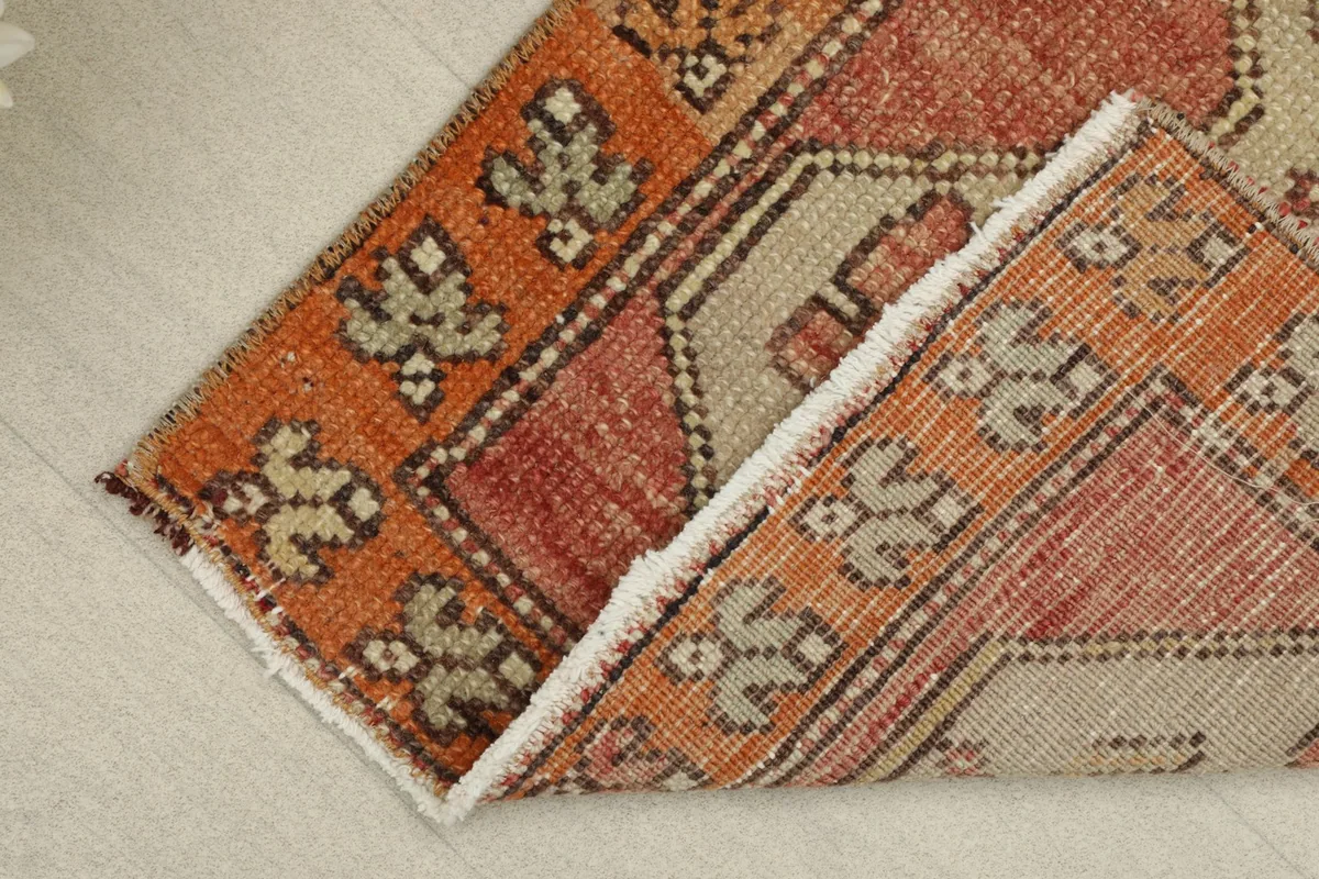 Rug partially folded, displaying the back of the hand-knotted cotton foundation and wool pile.