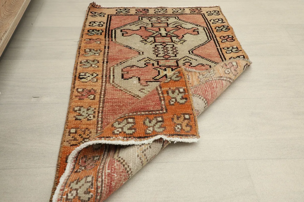 The mini area rug folded over, showing its flexibility and the reverse side of the weave.