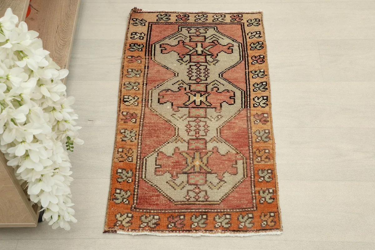 Direct overhead shot of the vintage Anatolian rug, showcasing its rose, beige, and orange geometric design.