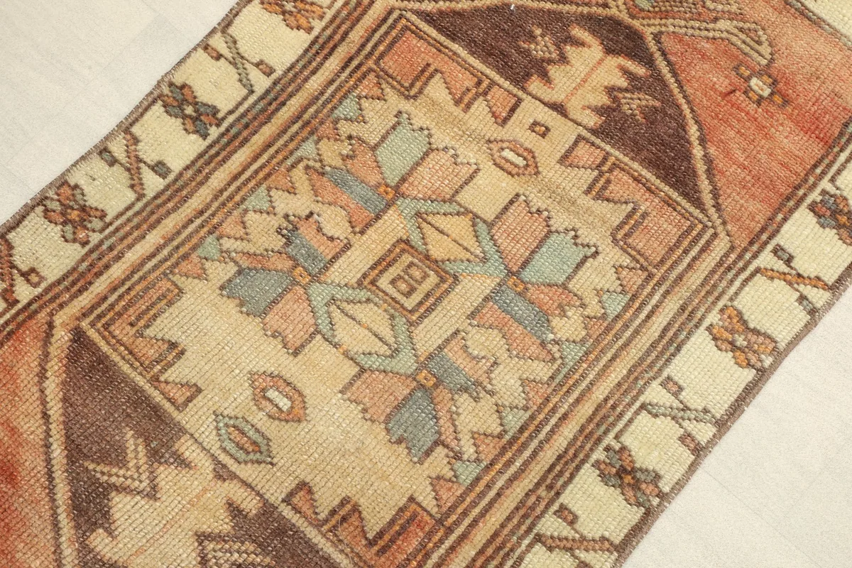Angled view highlighting the central geometric design and border details of the vintage rug.