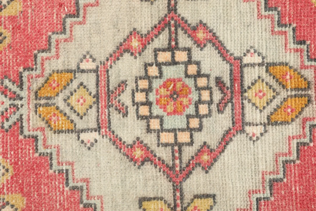 Detailed shot of the intricate geometric patterns and colors within the central ivory medallion of the rug.