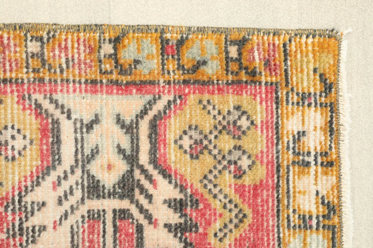 Close-up of the tribal motifs and the gold border along one side of the vintage rug.