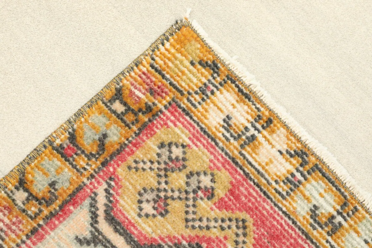 Corner detail showing the gold and black patterned border and the short fringe of the rug.