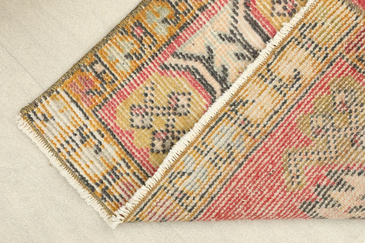 View of the rug folded to show the wool pile texture and the cotton foundation on the back.