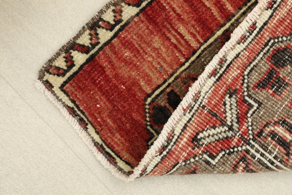 View of the rug folded to show the flexibility and thickness of the vintage hand-knotted wool construction.