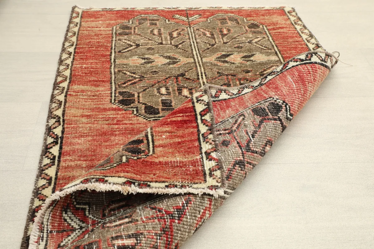 The rug partially folded, displaying the back of the cotton foundation and the overall design from an angle.