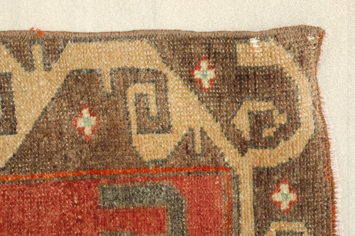 Close-up of the border pattern, revealing the wool pile texture and slight wear.