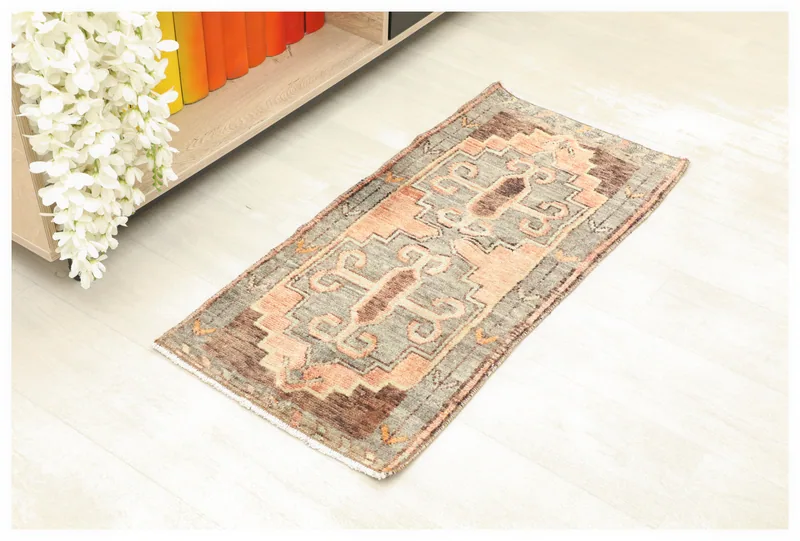 Full top view of the 1'5" x 3'2" charcoal and rose vintage Anatolian area rug on a white floor.