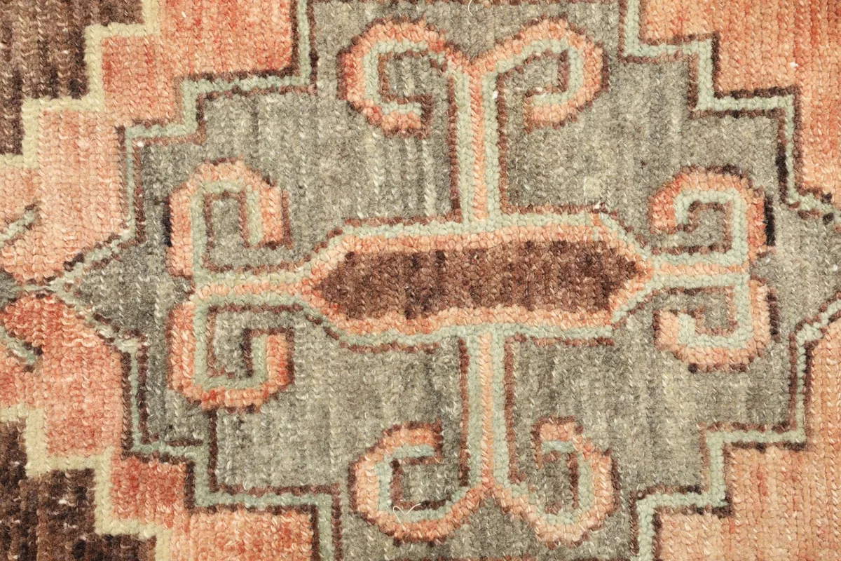 Detailed view of the rug's geometric pattern, showcasing the intricate knotting and color variations.