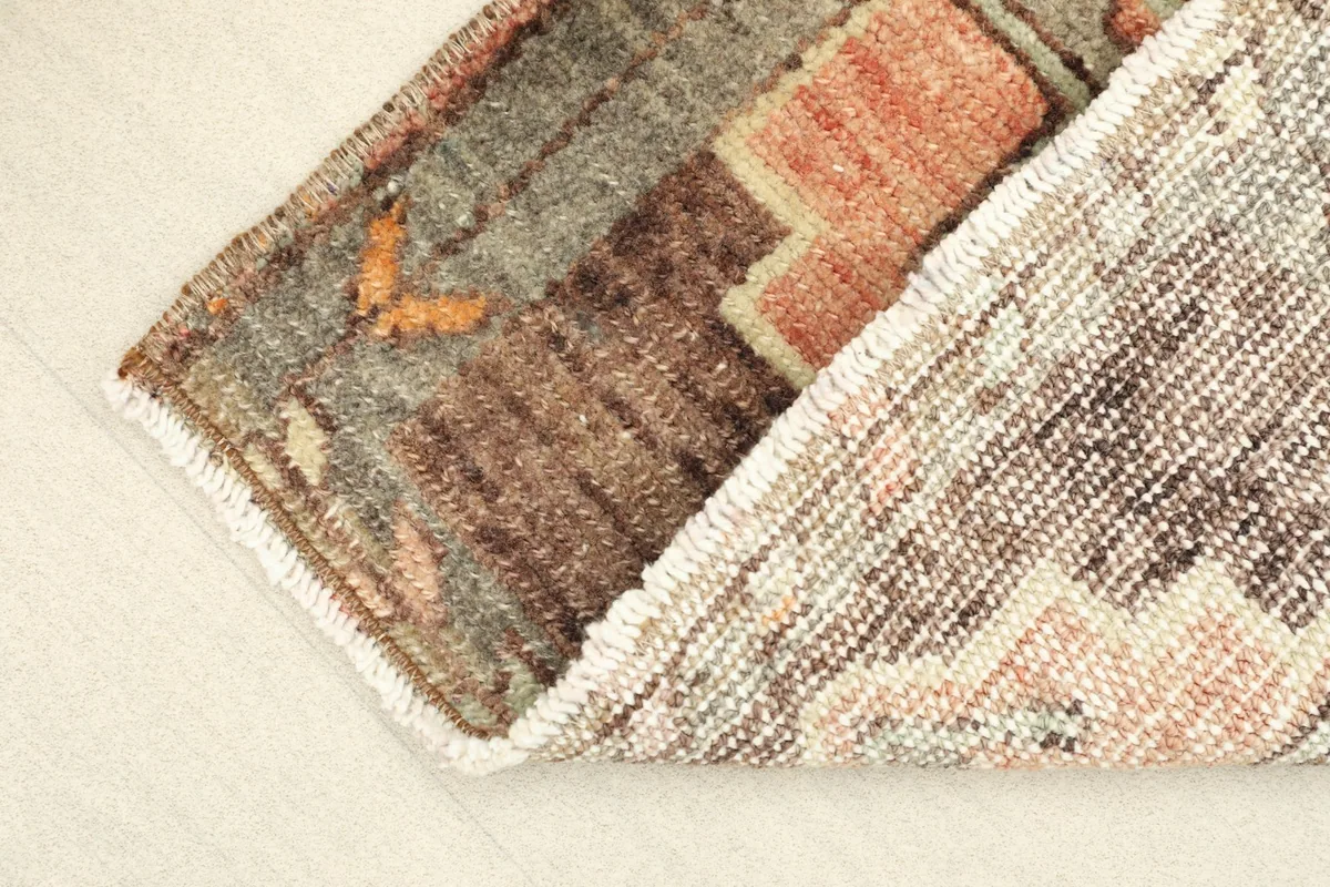 Partial view of the rug's underside, showing the cotton foundation and hand-knotted construction.