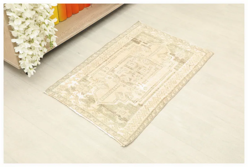 Full top view of the 1'9" x 2'10" cream and olive vintage Anatolian doormat rug on a light floor.