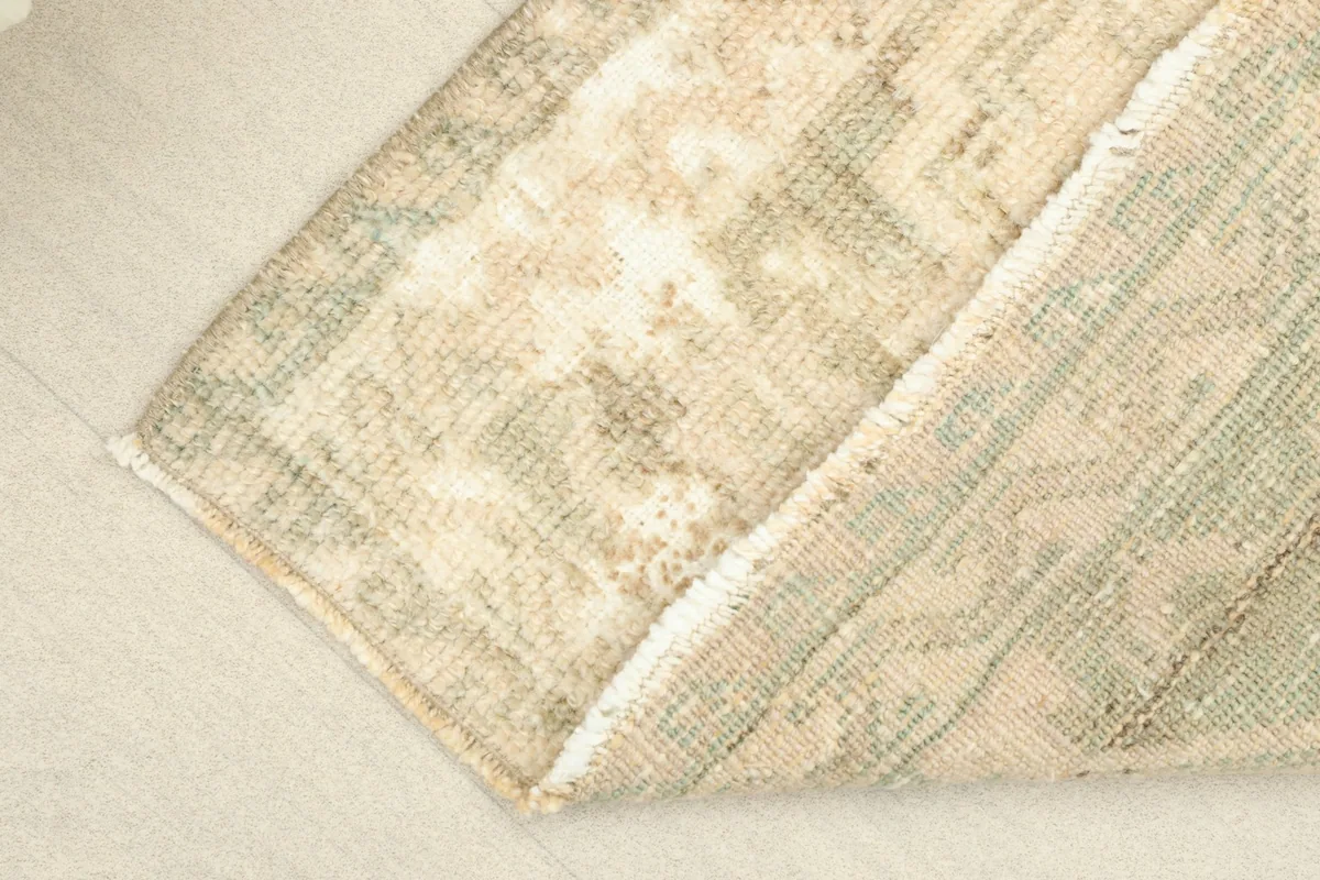 View of the rug's backside, revealing the cotton foundation and knotting structure.