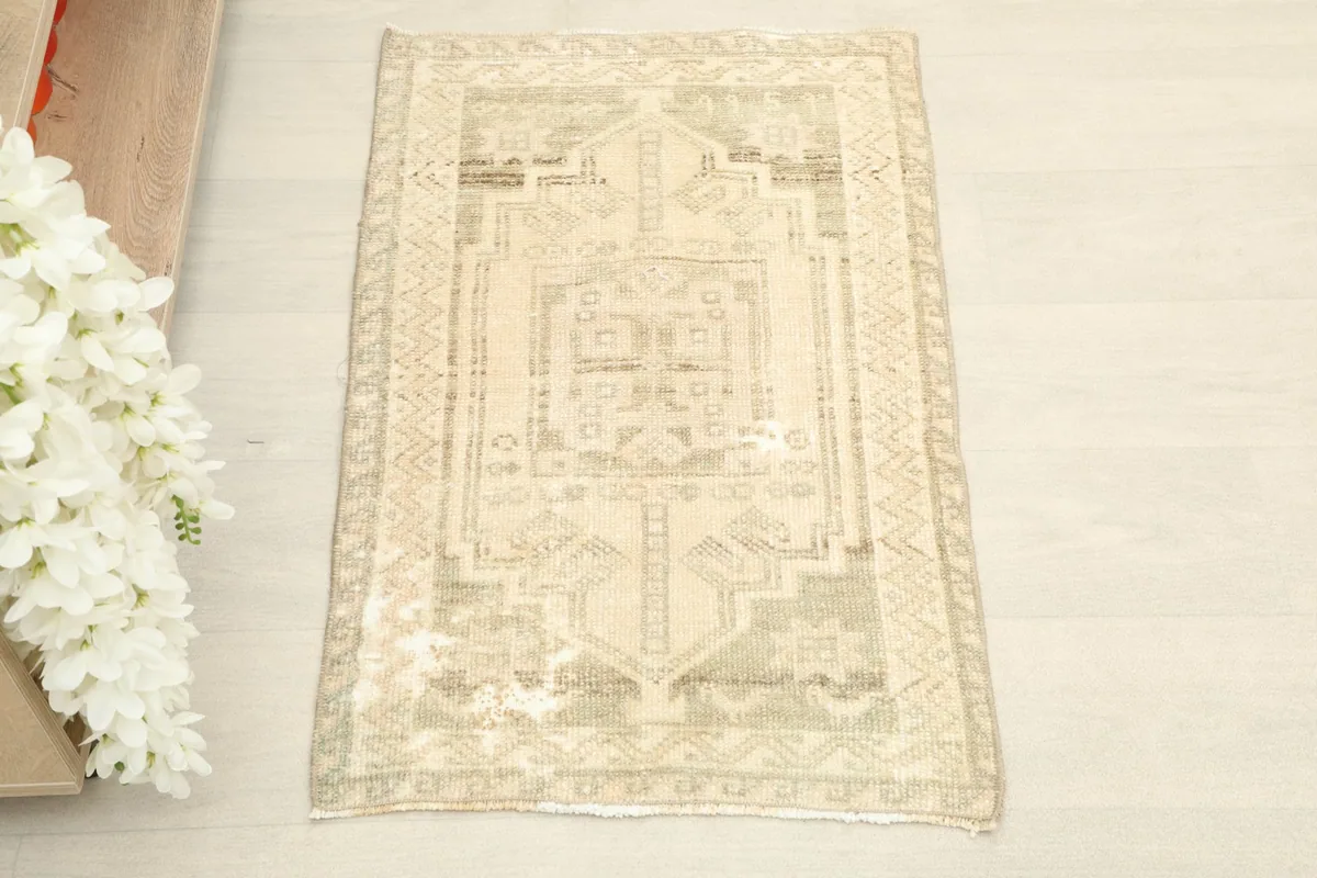 Overhead shot of the small hand-knotted rug, highlighting its cream field and olive geometric patterns.