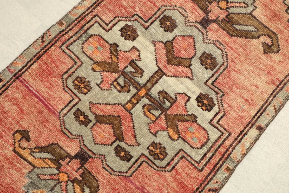 Close-up detail of the central geometric medallion and surrounding motifs in gray, brown, and rose.