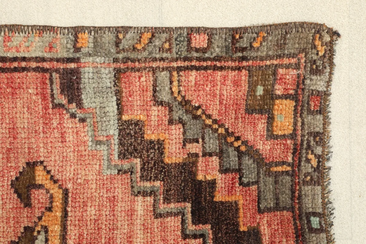 Edge detail of the rug, highlighting the stepped geometric patterns in the border and the rose field.