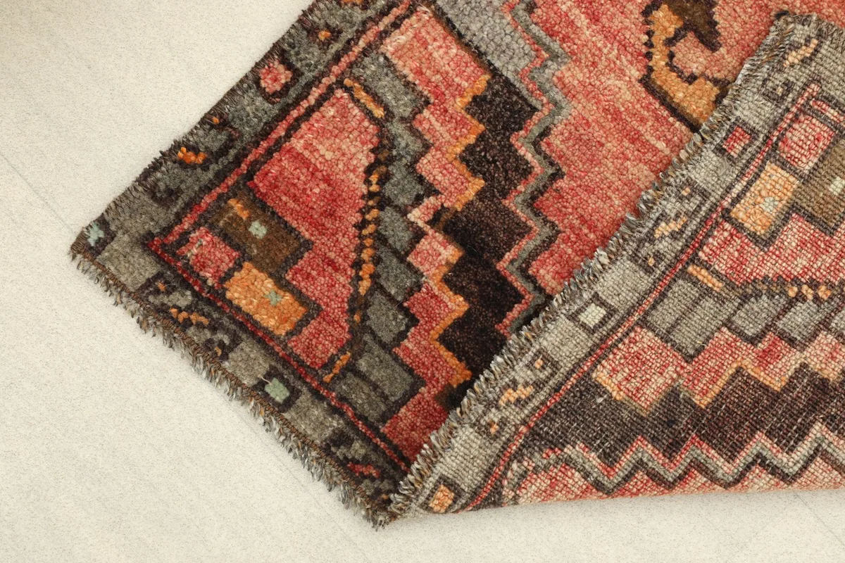 The rug partially folded, showing the texture of the low wool pile and the hand-knotted construction.