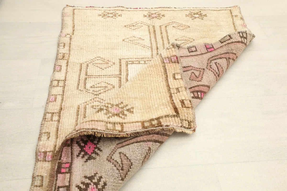 Partially folded rug, displaying both the front design and the reverse side with its muted colors.