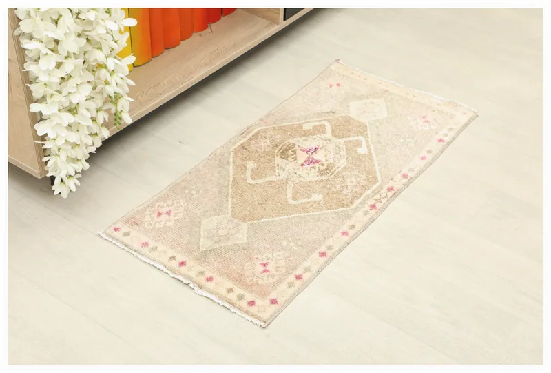 Full top view of the beige and pink geometric Anatolian vintage rug on a white background.