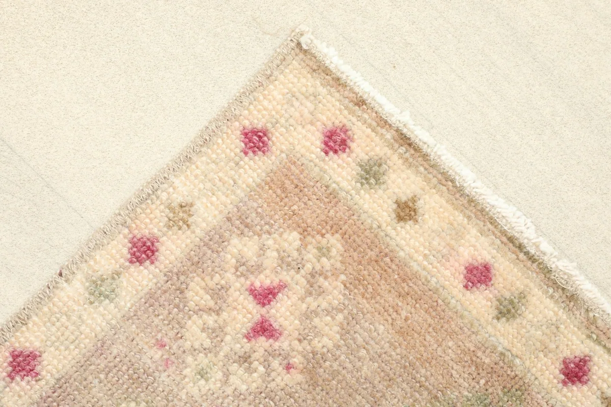 Corner view showing the simple border design with small pink and olive geometric elements.