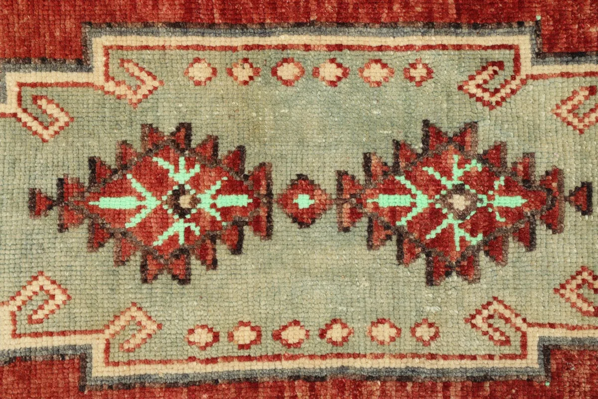 Detailed view of the intricate geometric patterns within the green medallion and the surrounding motifs.