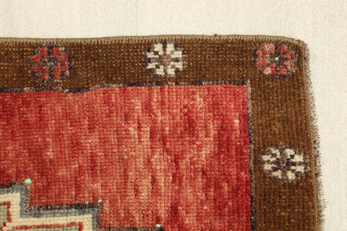 Close-up of a corner, highlighting the brown border, rust field, and the hand-knotted texture.