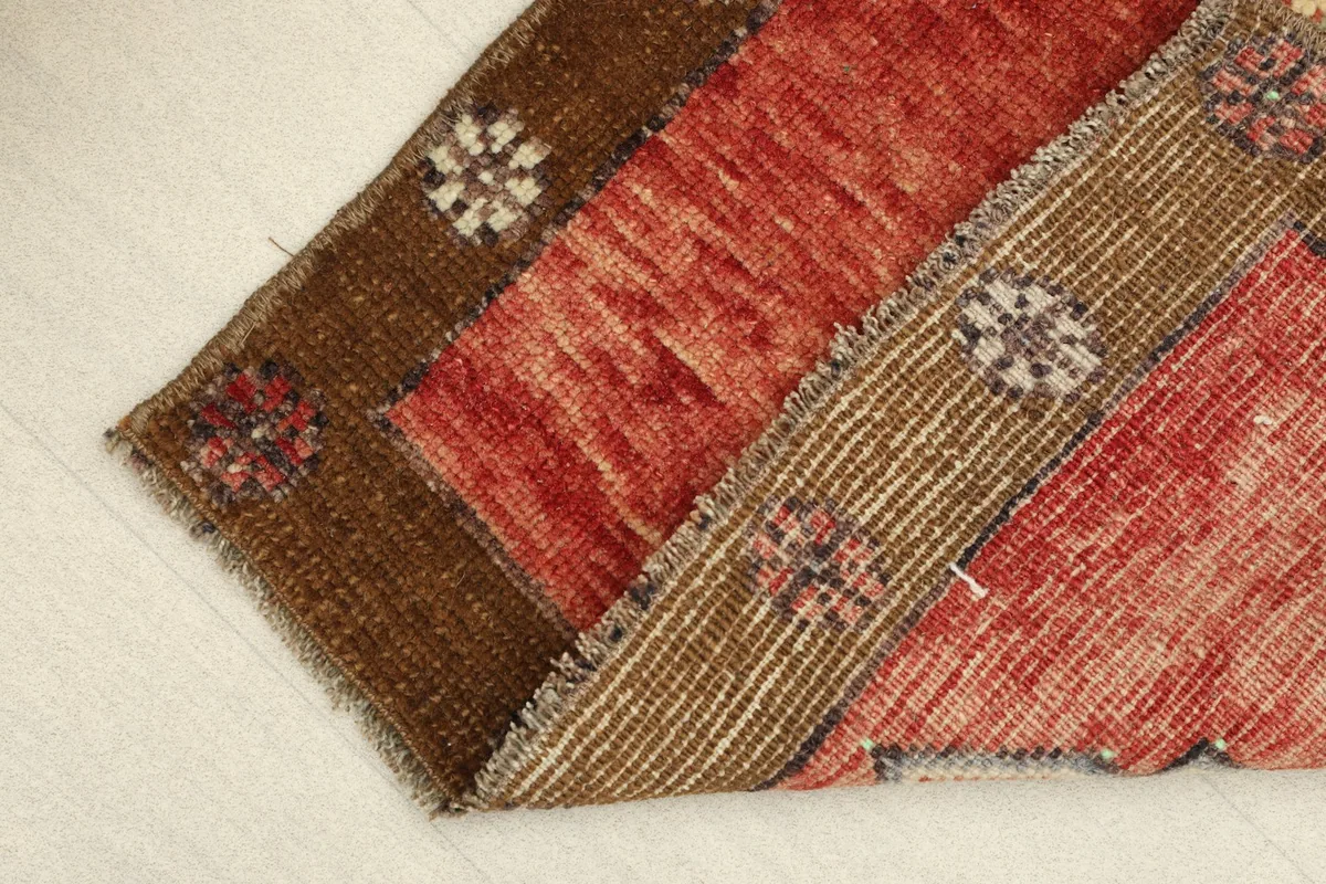 View of the rug folded to show the low wool pile and the hand-knotted construction from the side.