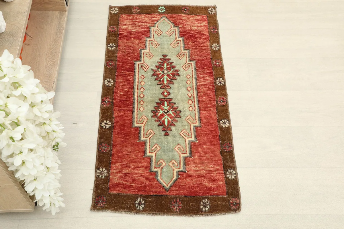 Straight overhead view of the small hand-knotted rug, highlighting its rust, green, and brown colors.