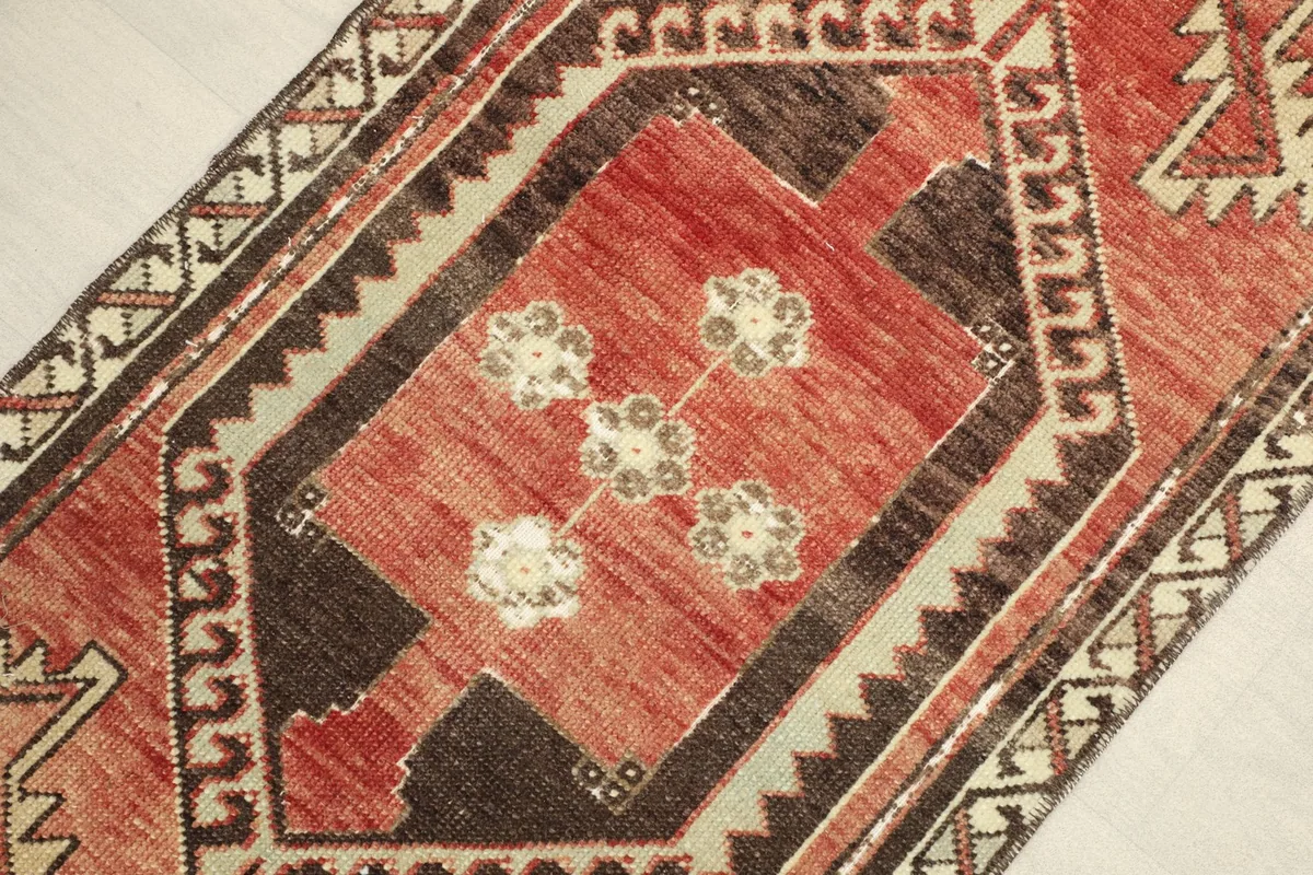 Close-up of the central red field with ivory and brown floral motifs, surrounded by a dark brown border