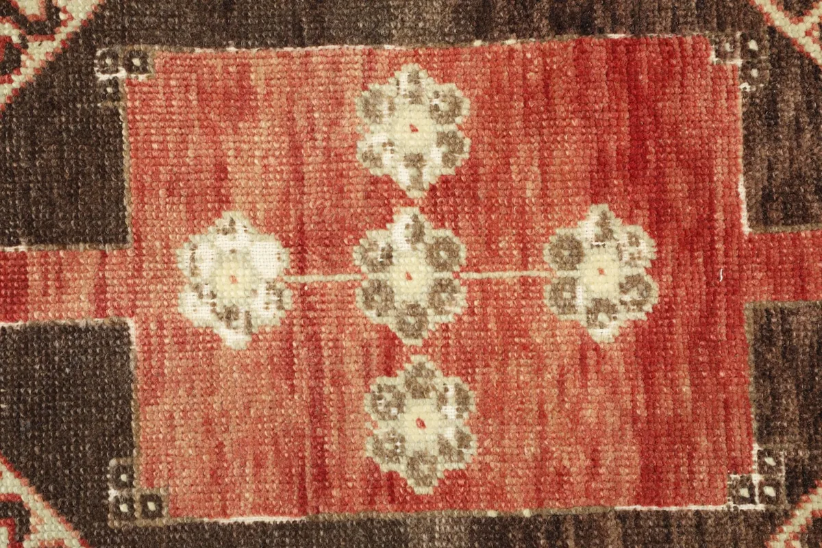Detailed view of the central red area rug motif, showing the faded floral elements and texture