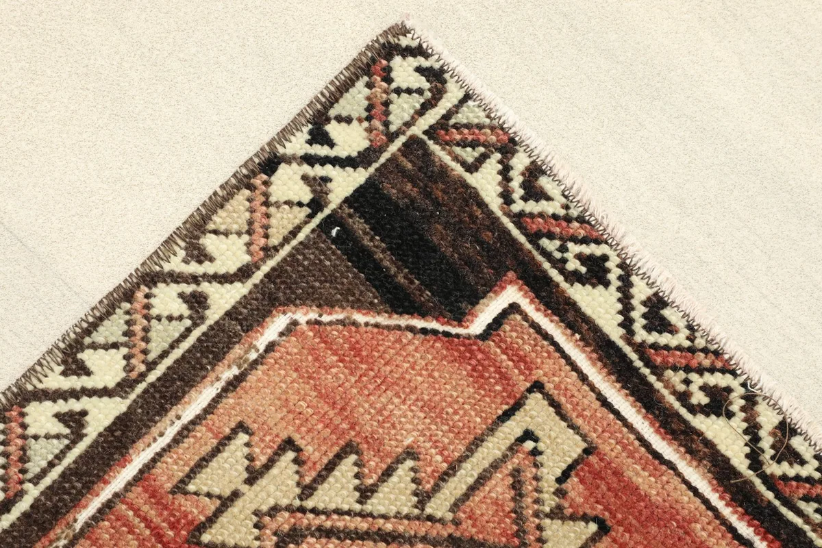 Corner detail of the rug's border, showcasing the beige and brown geometric patterns and knotting