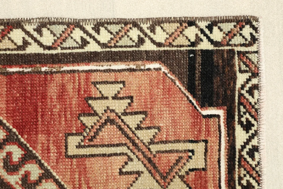 Close-up of the rug's edge, showing the intricate beige and brown tribal border design and low pile