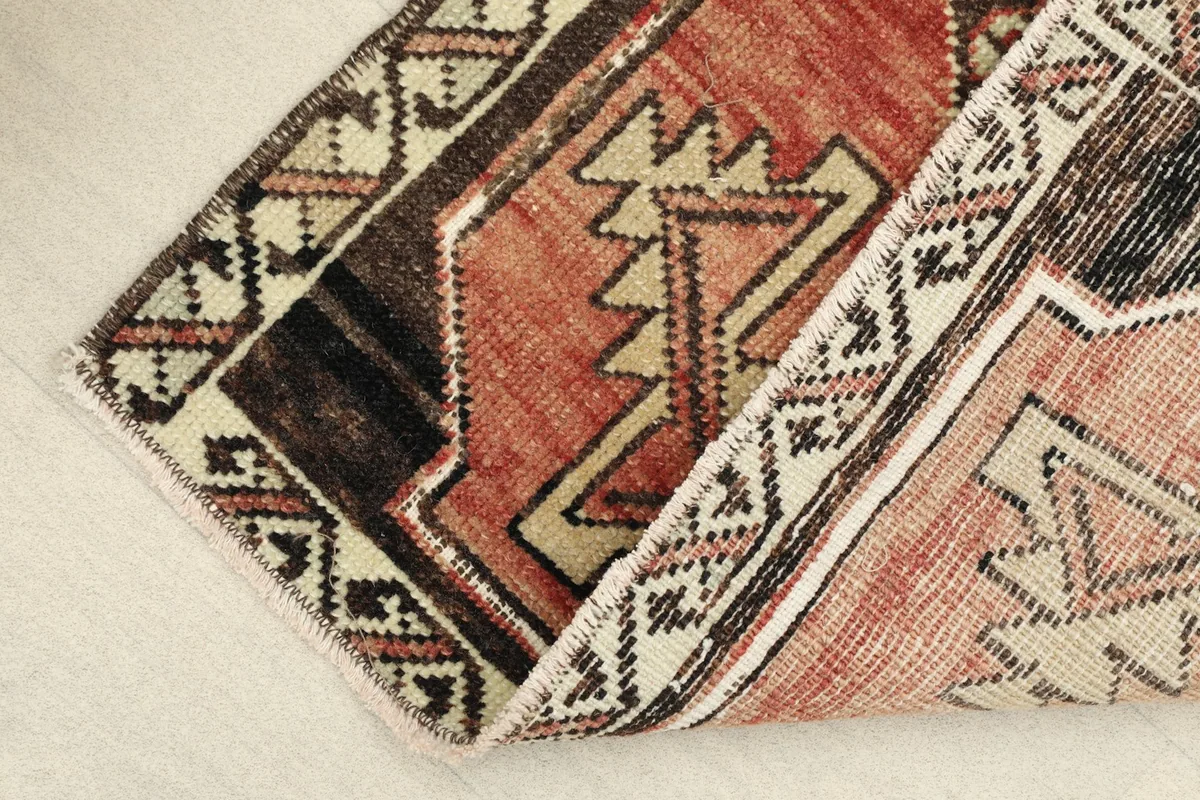 Angle view of the rug folded, revealing the low pile and texture of the hand-knotted wool