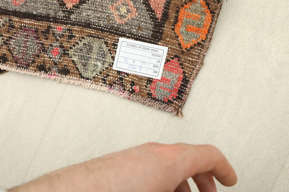 Back of the rug with a hand visible for scale, showing the cotton foundation and knotting.