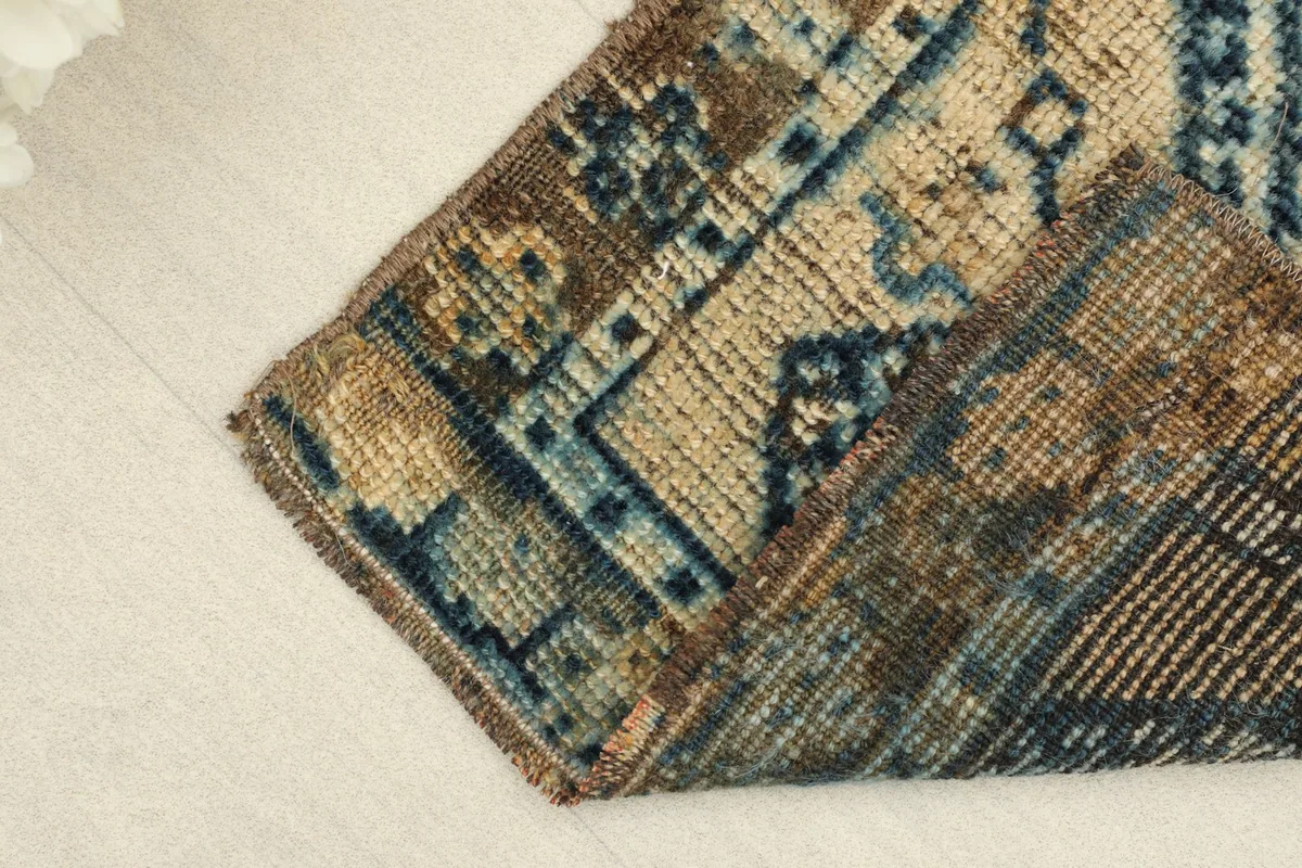 A folded section of the rug, revealing the thickness of the wool pile and the reverse side.
