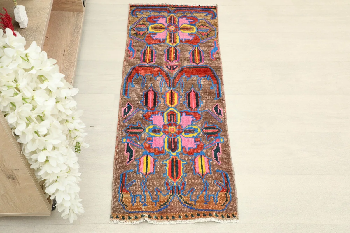 Overhead view showcasing the intricate pink, blue, yellow, and orange geometric patterns on the brown field.