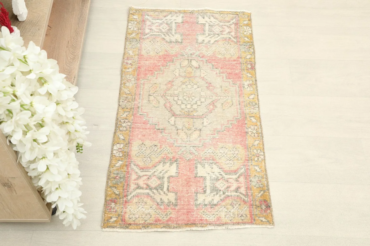 Overhead view of the hand-knotted wool rug, highlighting its rose, beige, and gold colors