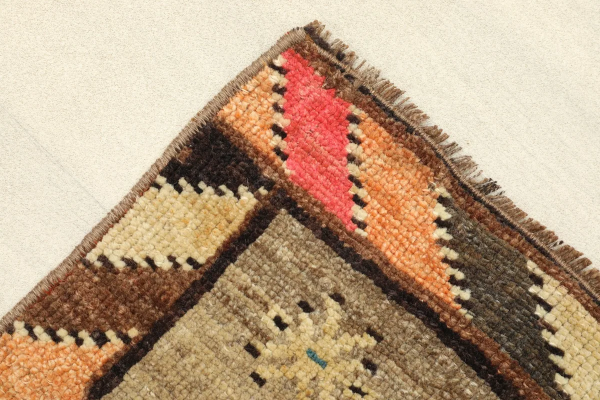 Corner detail of the rug, showing the vibrant striped border in red, orange, and brown tones.