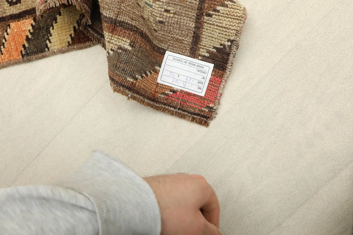Close-up of the rug's backside, displaying the hand-knotted construction and a product label.
