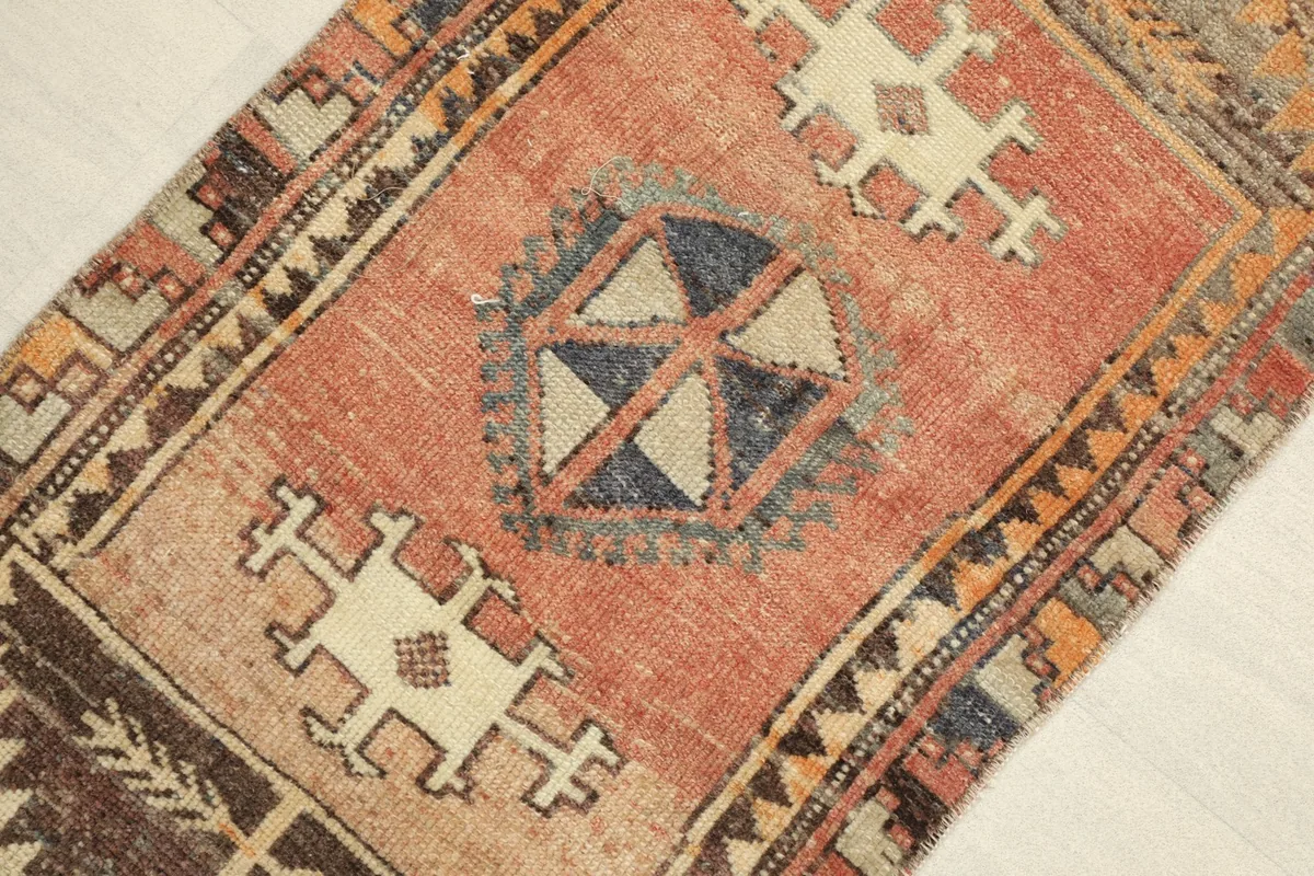 Close-up angled view of the rug's central rust orange field with geometric motifs and border patterns.