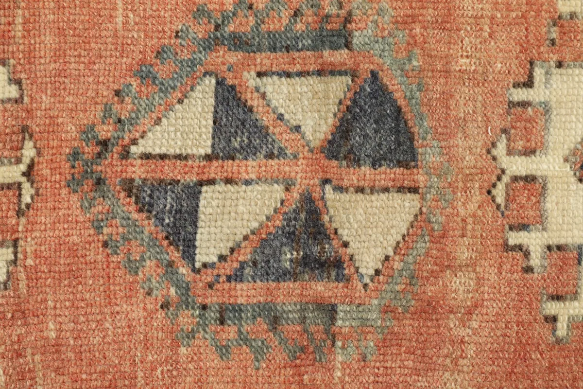 Detailed close-up of the central geometric medallion in navy, beige, and rust orange.