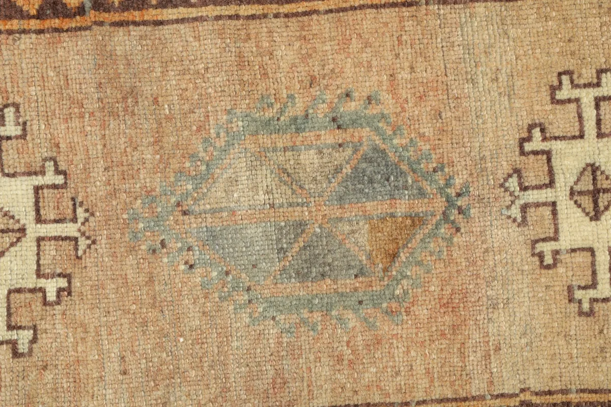 Detailed view of the central geometric motif and the subtle color variations in the beige pile.