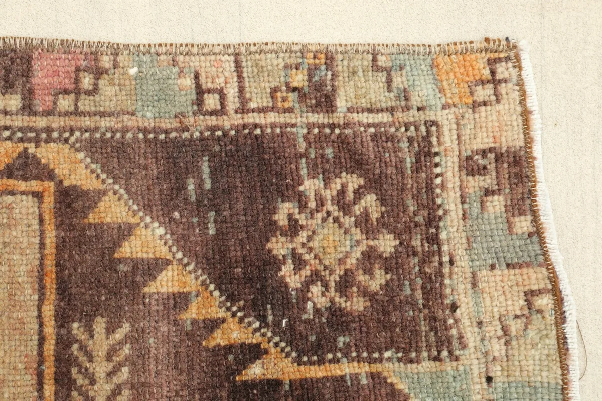 Close-up of the brown border and corner motif, with accents of rust, blue, and beige.