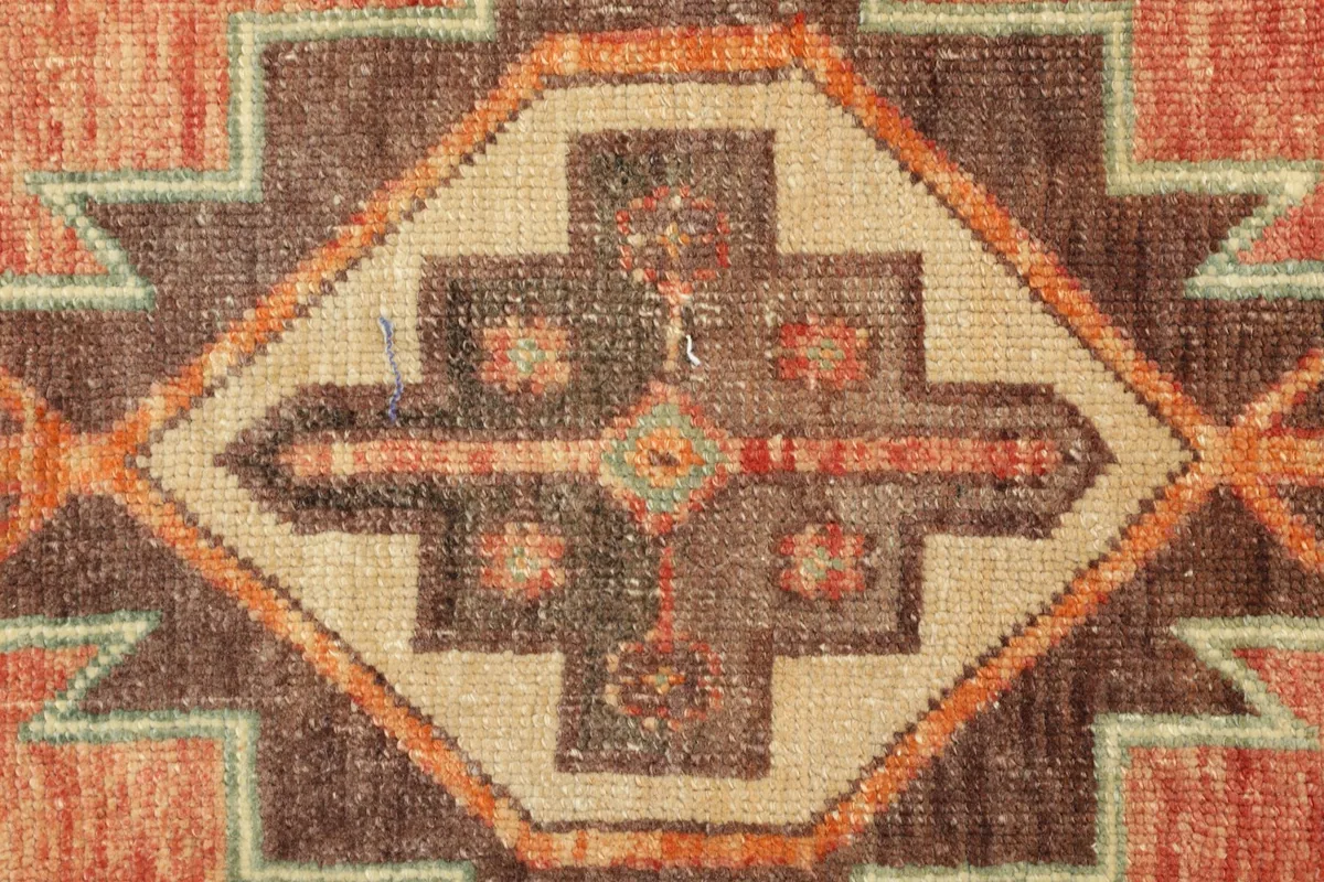 Detailed view of a central geometric motif in brown, tan, and green with orange accents.