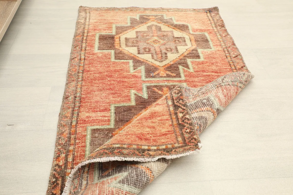 Another view of the rug partially folded, emphasizing its construction and vintage condition.