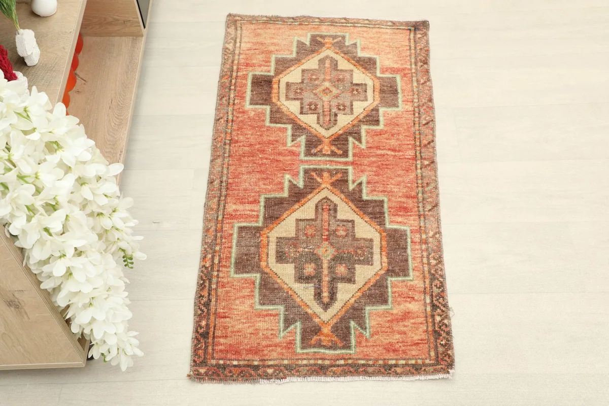 Overhead view showcasing the rust field and brown, tan, green geometric motifs of the small area rug.