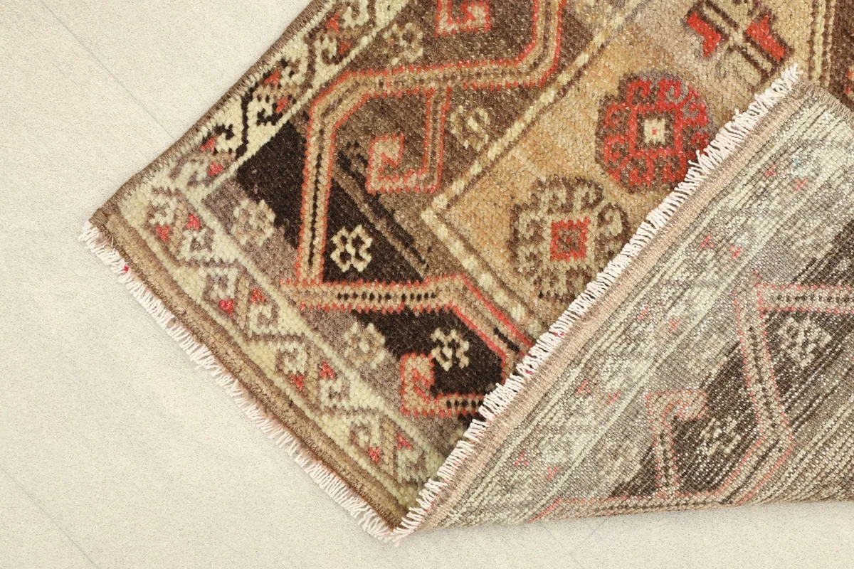 Partial view of the rug's back, showing the cotton foundation and hand-knotting