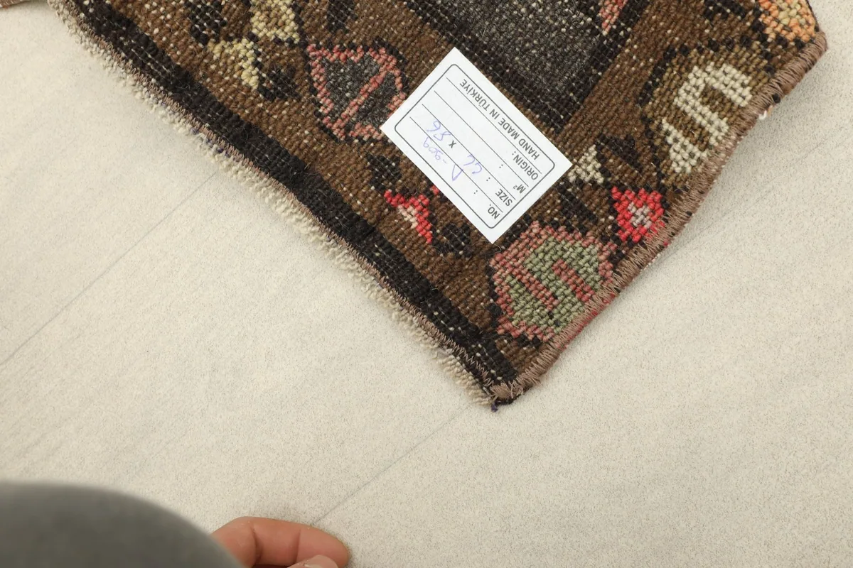 Underside view of the rug, revealing the hand-knotted construction and a product label.